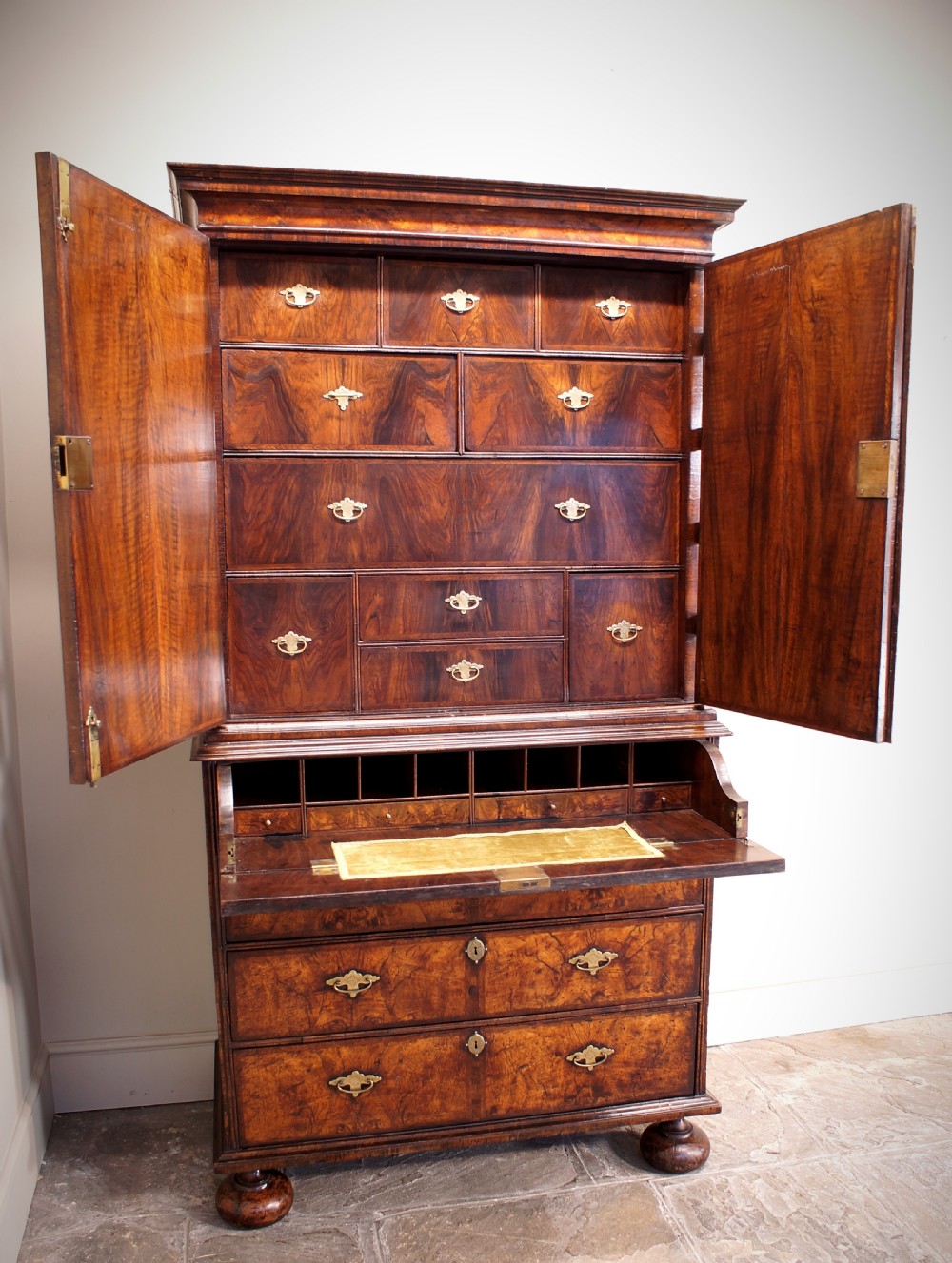 An early eighteenth-century burr walnut cabinet on chest featuring double upper doors with brass strap hinges above four graduated drawers, resting on turned bun feet. View XXIII