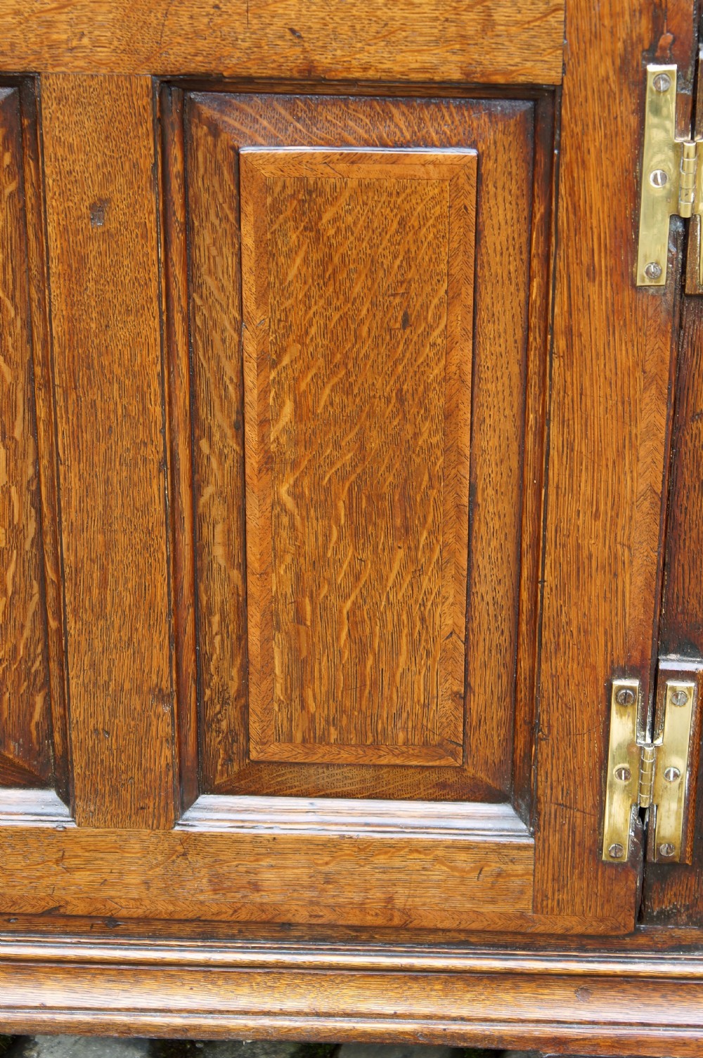 An 18th-century oak dresser base featuring multiple drawers, a central panelled cupboard door, brass handles, and bracket feet. View IX