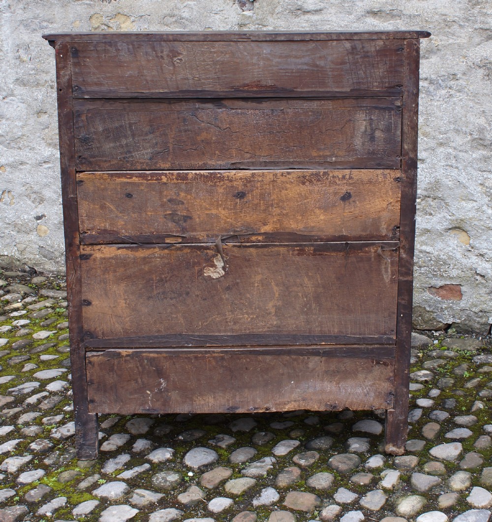A dark oak 17th century hutch featuring panelled doors, hand-forged iron strap hinges, applied split turnings, and top edge dentil moulding. View VIII