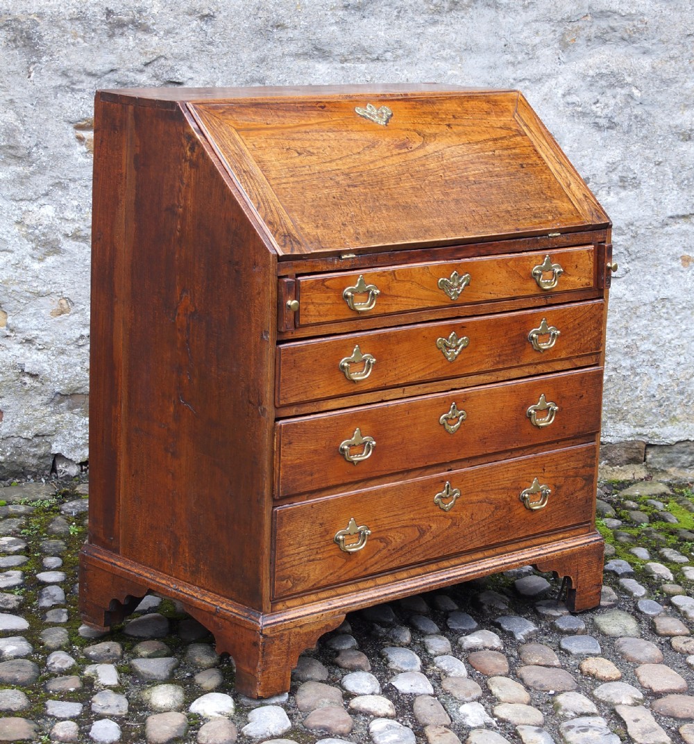 An early eighteenth-century elm slant-front bureau featuring four graduated drawers with brass drop handles and bracket feet. View III