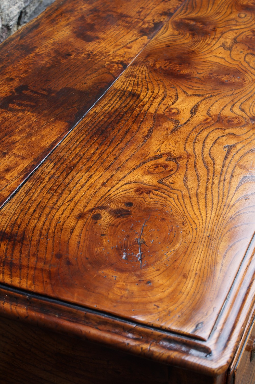 An eighteenth-century warm brown elm dresser base featuring three primary drawers with brass handles above four small drawers set into a scalloped apron. View V