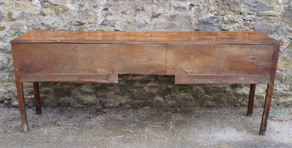 An eighteenth-century warm brown elm dresser base featuring three primary drawers with brass handles above four small drawers set into a scalloped apron. View XVI
