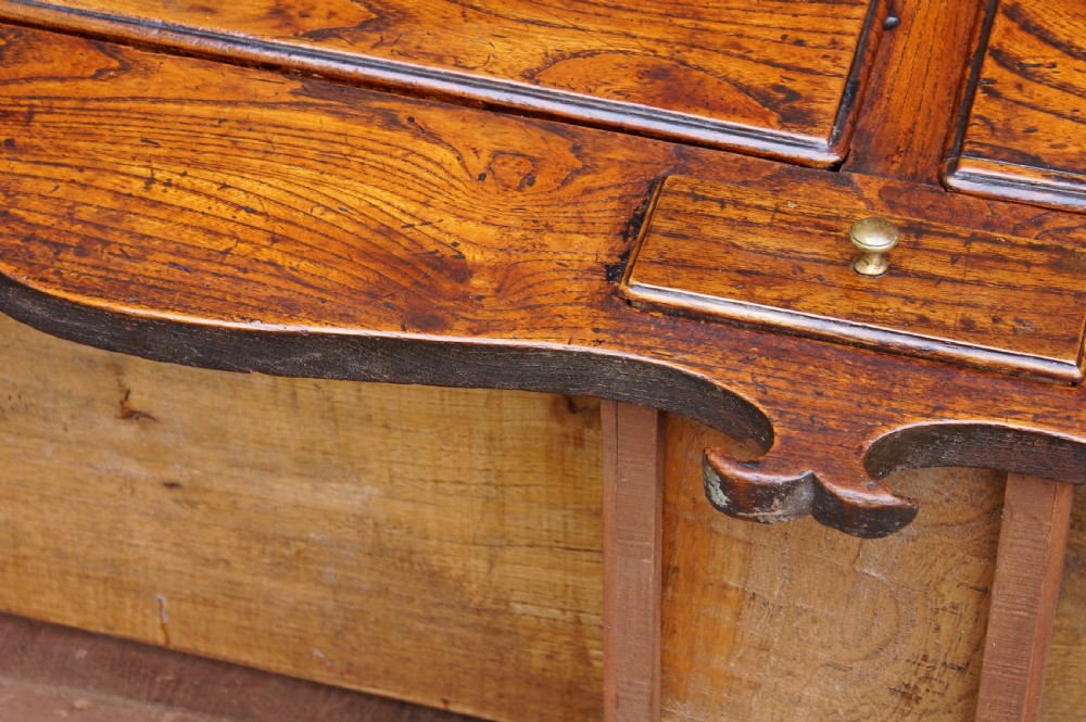 An eighteenth-century warm brown elm dresser base featuring three primary drawers with brass handles above four small drawers set into a scalloped apron. View XXI