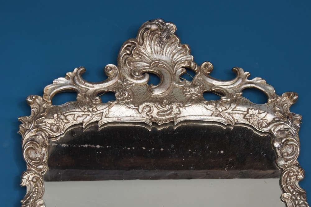 A large rectangular 18th century silver gilt wall mirror featuring an ornate carved frame with Rococo C-scrolls and shell cresting. View IV