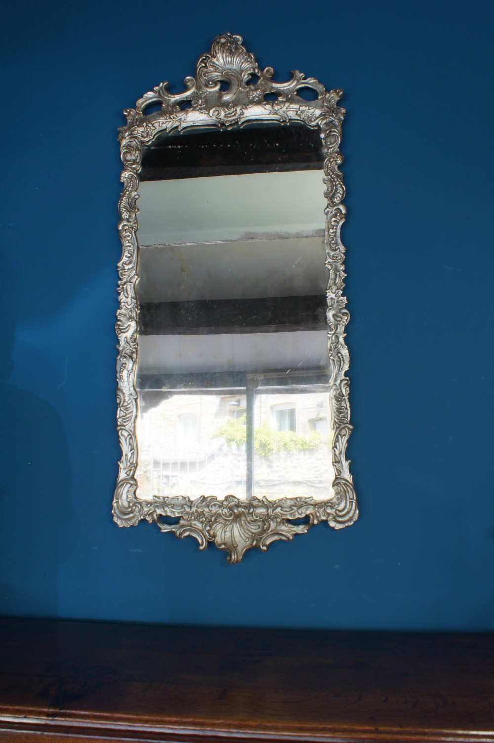 A large rectangular 18th century silver gilt wall mirror featuring an ornate carved frame with Rococo C-scrolls and shell cresting. View V