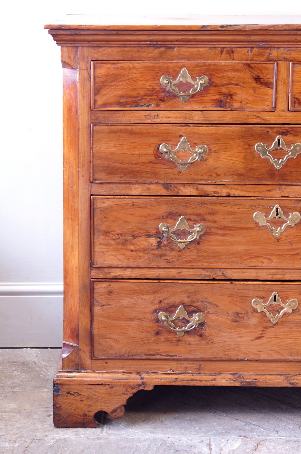 An 18th-century Georgian chest of drawers crafted from highly figured warm honey-toned yew wood with two short drawers over three long drawers and brass batwing handles. View VI