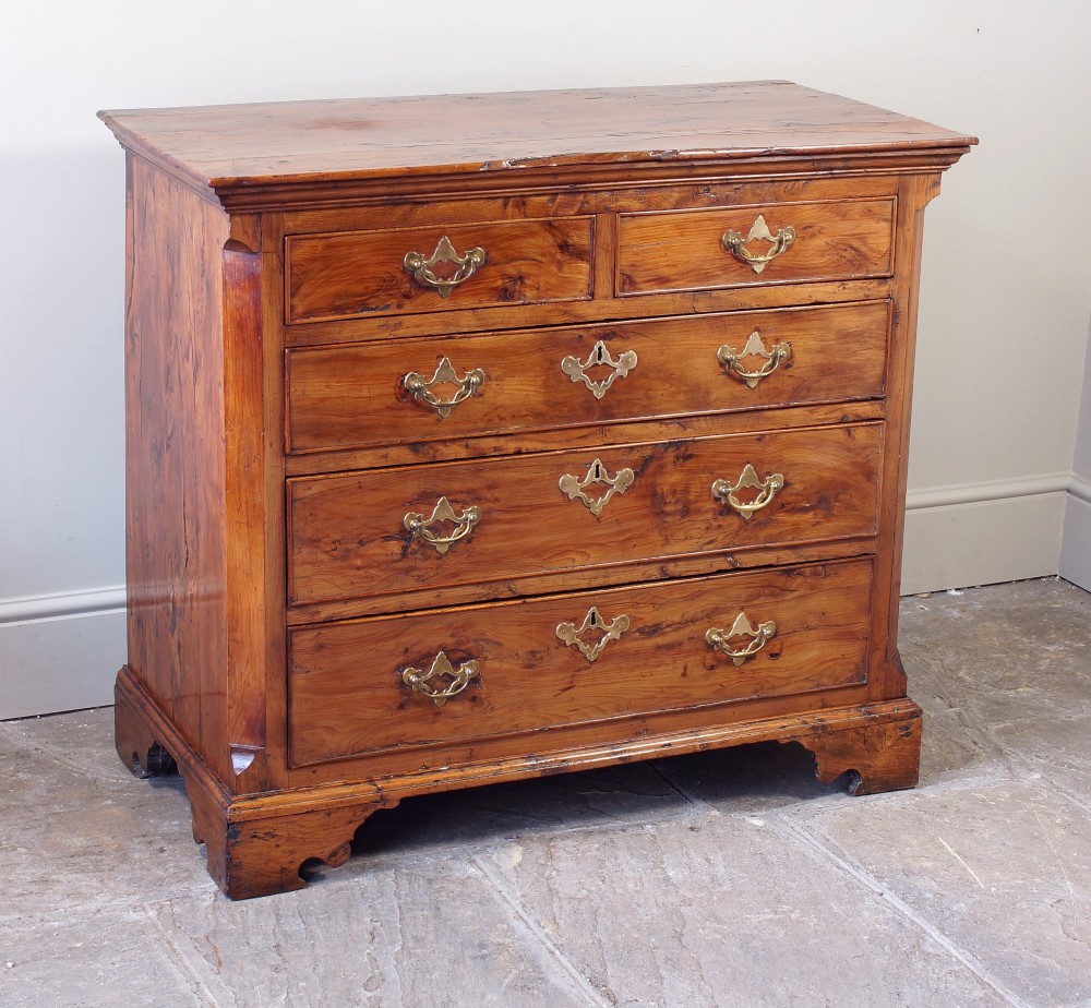 An 18th-century Georgian chest of drawers crafted from highly figured warm honey-toned yew wood with two short drawers over three long drawers and brass batwing handles. View II
