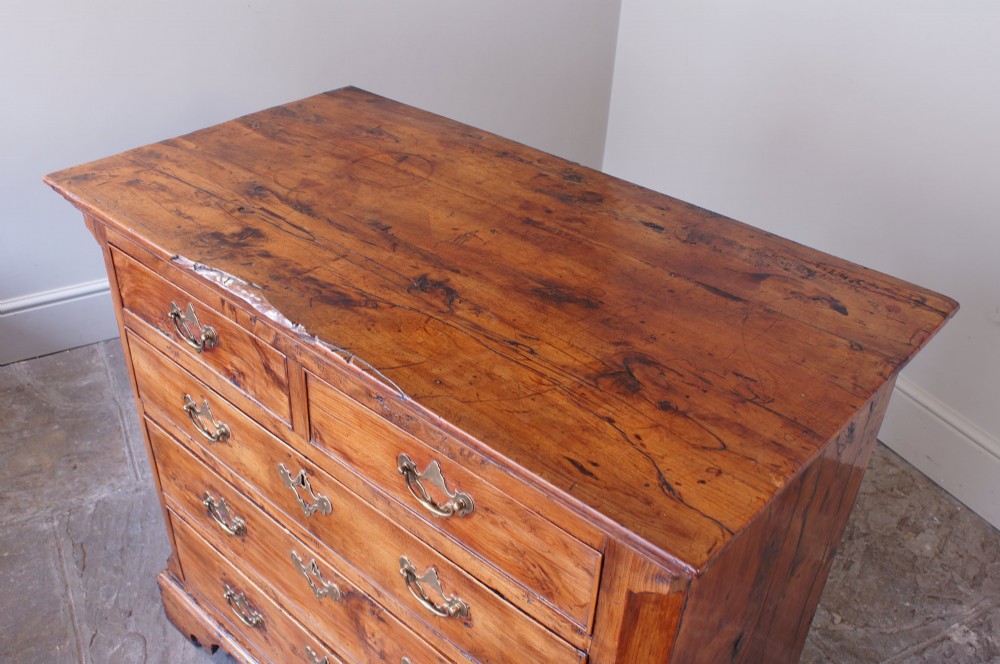 An 18th-century Georgian chest of drawers crafted from highly figured warm honey-toned yew wood with two short drawers over three long drawers and brass batwing handles. View X