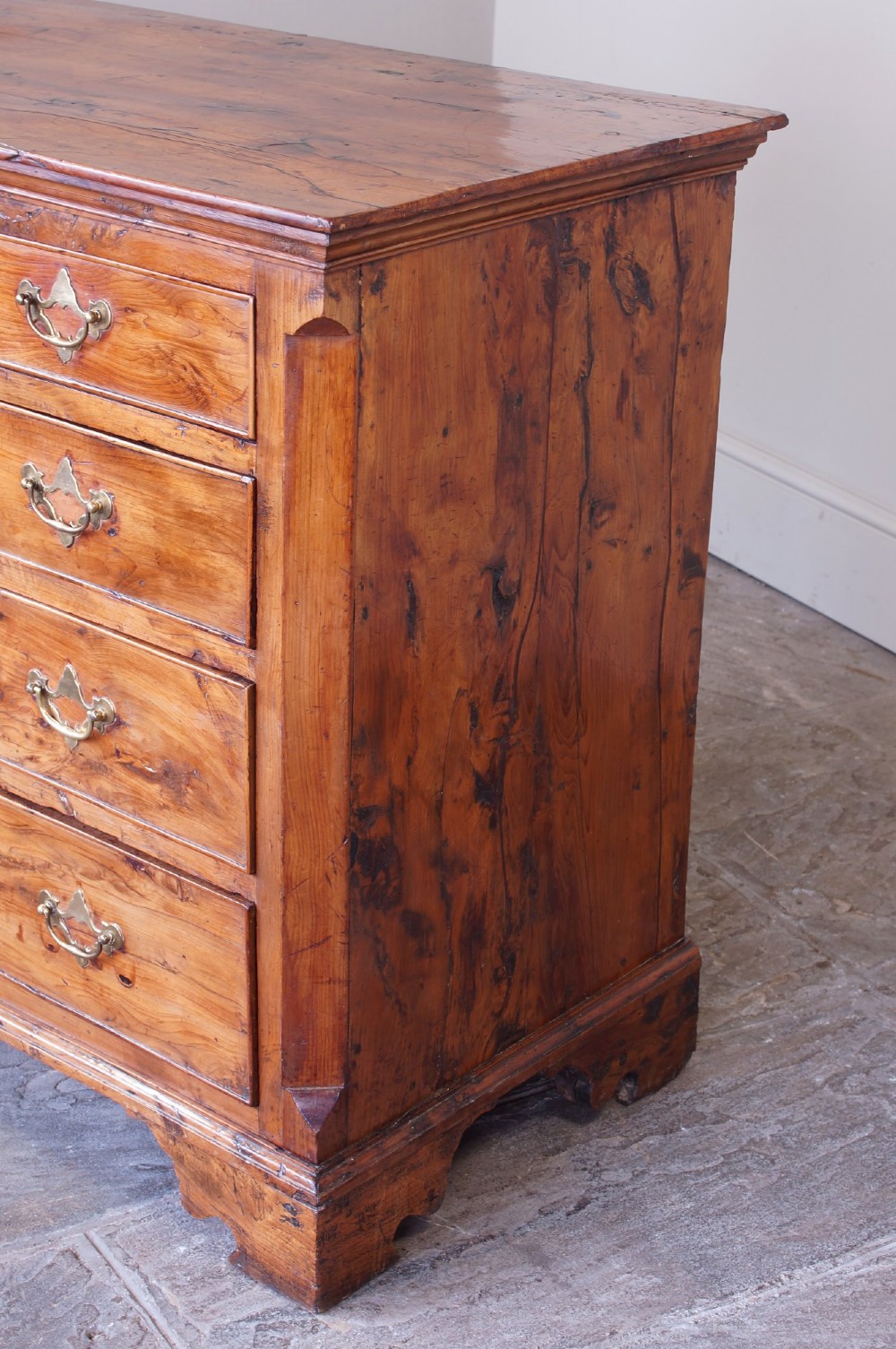 An 18th-century Georgian chest of drawers crafted from highly figured warm honey-toned yew wood with two short drawers over three long drawers and brass batwing handles. View XI