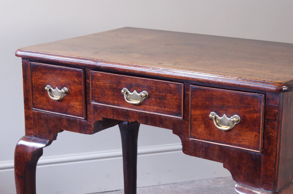 A mid-18th century George II mahogany lowboy featuring three drawers with brass handles, a shaped apron, and four cabriole legs ending in pad feet. View II