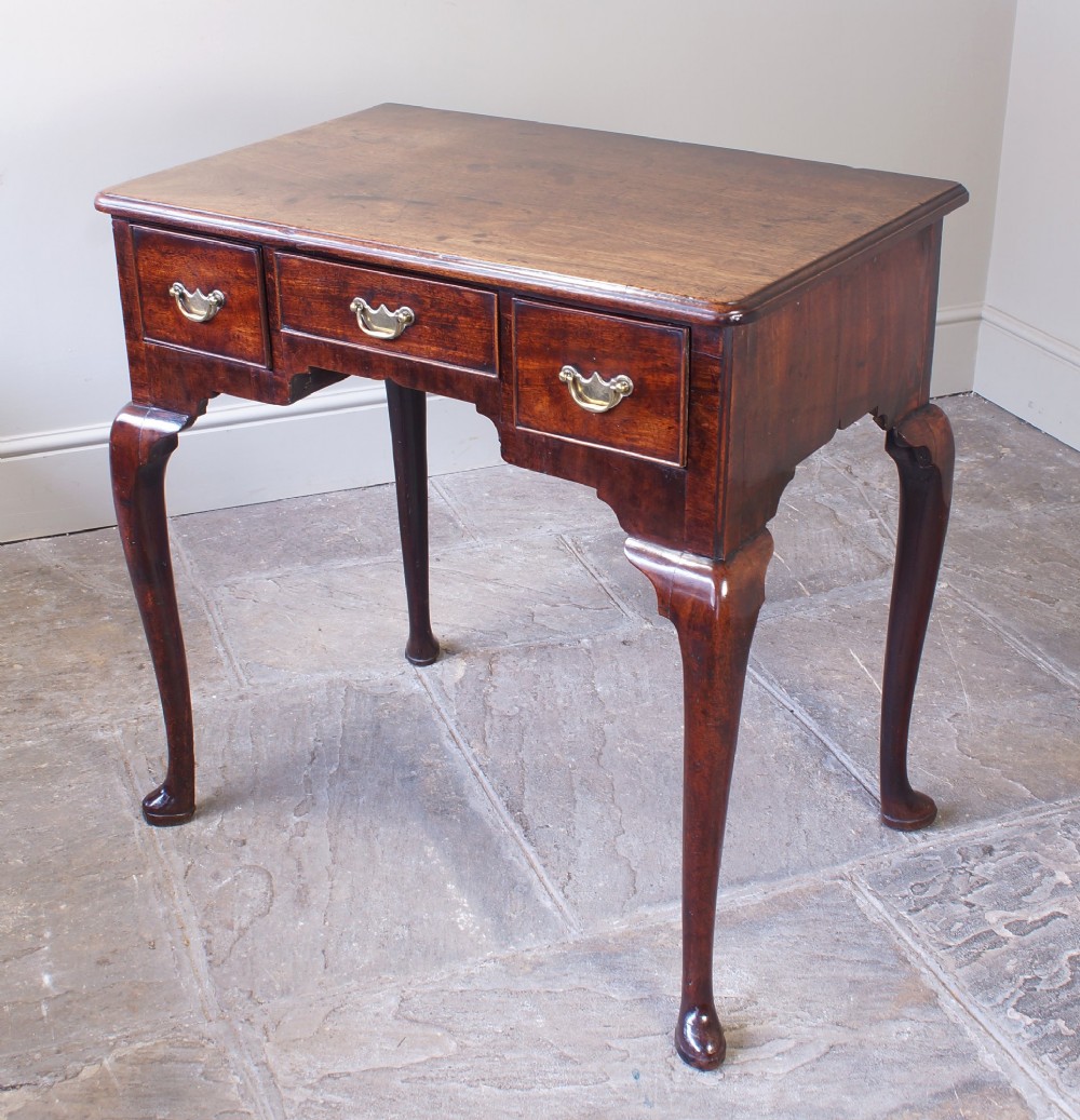 A mid-18th century George II mahogany lowboy featuring three drawers with brass handles, a shaped apron, and four cabriole legs ending in pad feet. View III