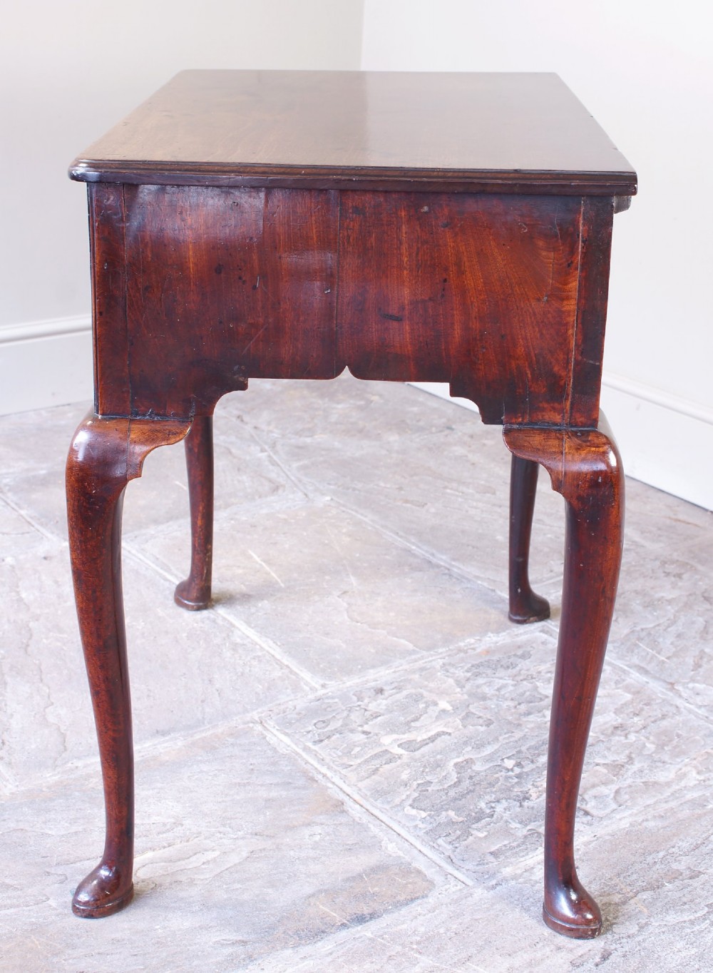 A mid-18th century George II mahogany lowboy featuring three drawers with brass handles, a shaped apron, and four cabriole legs ending in pad feet. View V