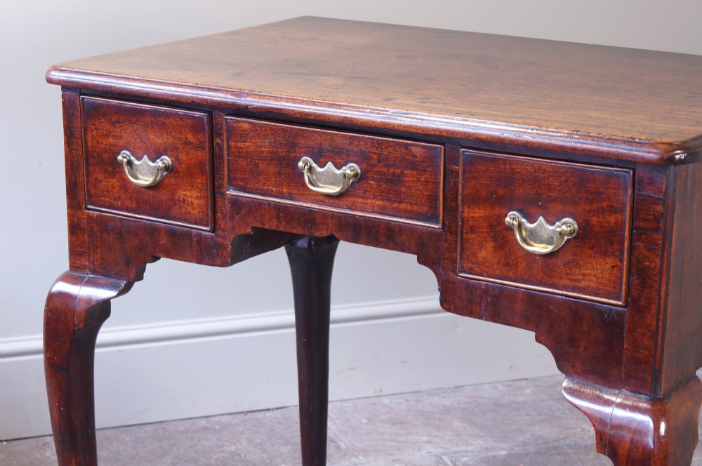 A mid-18th century George II mahogany lowboy featuring three drawers with brass handles, a shaped apron, and four cabriole legs ending in pad feet. View VII