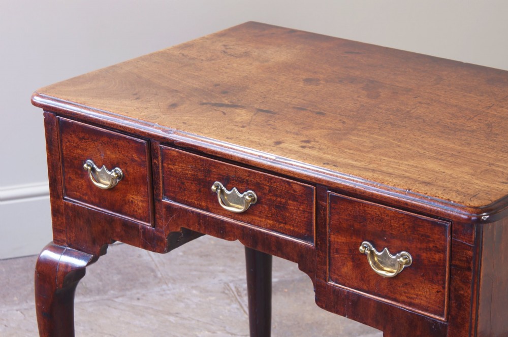 A mid-18th century George II mahogany lowboy featuring three drawers with brass handles, a shaped apron, and four cabriole legs ending in pad feet. View XI