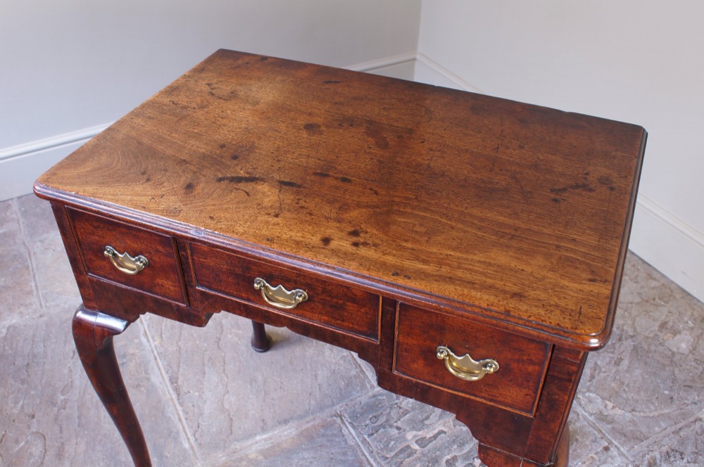 A mid-18th century George II mahogany lowboy featuring three drawers with brass handles, a shaped apron, and four cabriole legs ending in pad feet. View XII