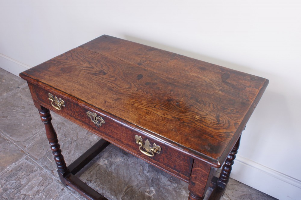 A late 17th-century dark oak side table featuring a single drawer with brass handles, turned legs, and a rectangular stretcher base. View III