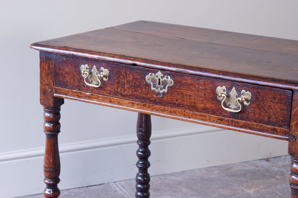 A late 17th-century dark oak side table featuring a single drawer with brass handles, turned legs, and a rectangular stretcher base. View IV