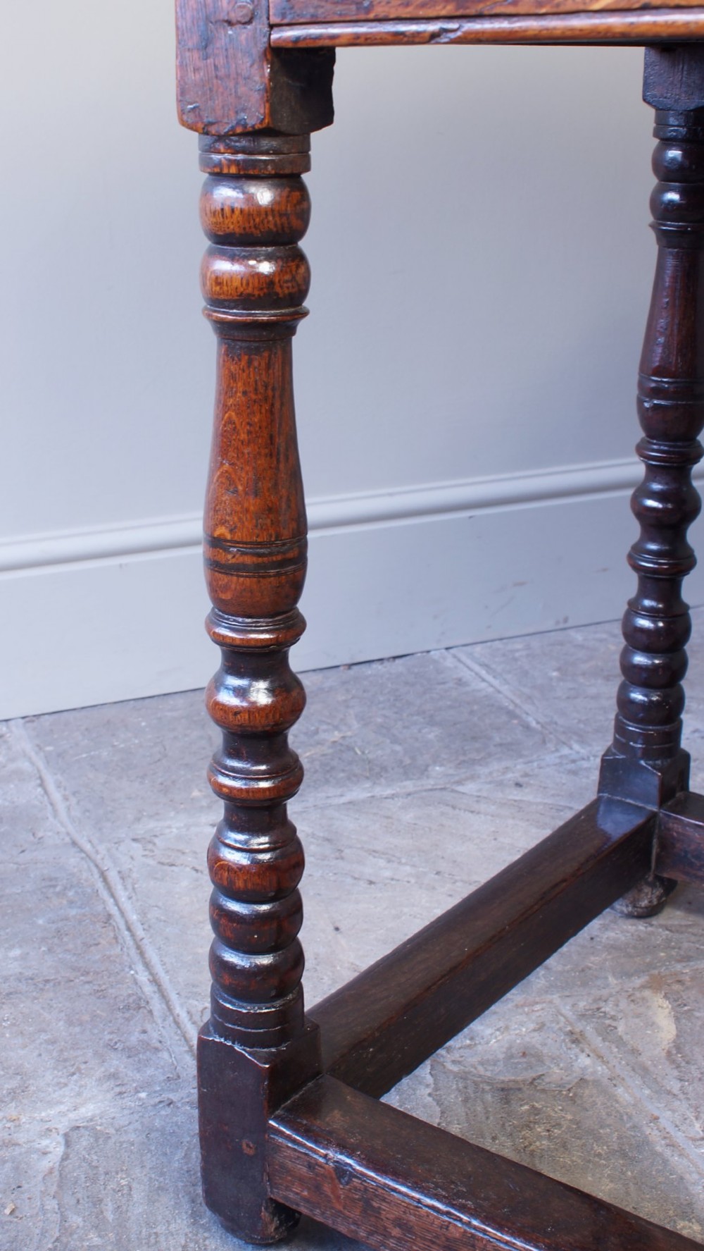A late 17th-century dark oak side table featuring a single drawer with brass handles, turned legs, and a rectangular stretcher base. View XII