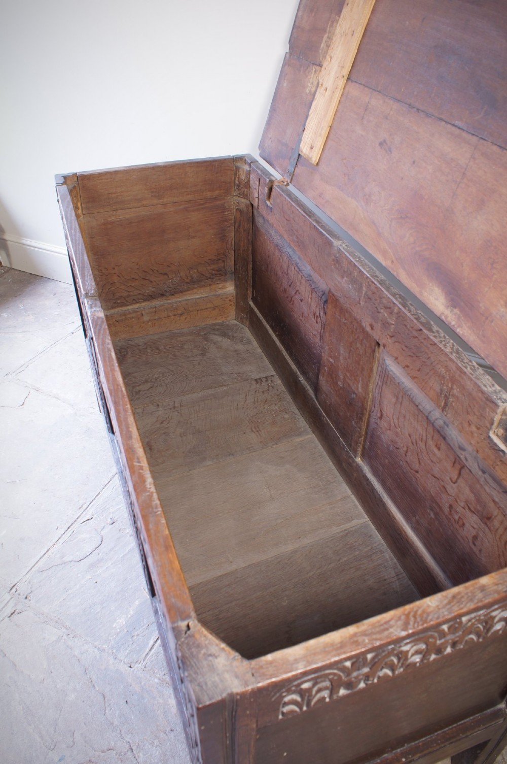 A 17th-century dark oak coffer with three carved floral panels, an iron lock plate, and a dated inscription reading FH 1683 along the front rail. View II