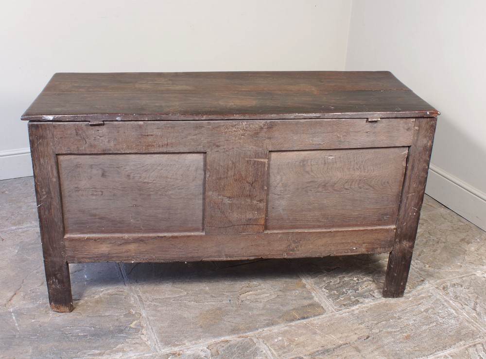 A 17th-century dark oak coffer with three carved floral panels, an iron lock plate, and a dated inscription reading FH 1683 along the front rail. View III