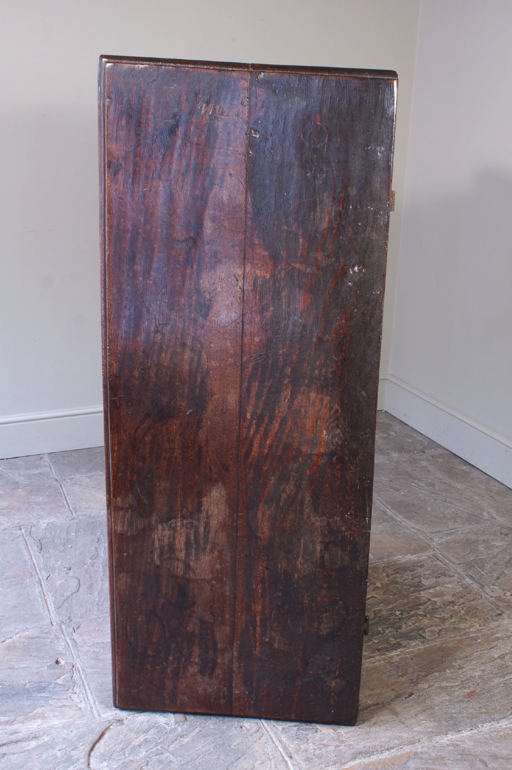 A 17th-century dark oak coffer with three carved floral panels, an iron lock plate, and a dated inscription reading FH 1683 along the front rail. View VII