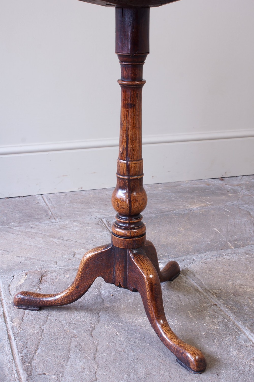 An 18th-century dark oak tripod table featuring a circular top, turned central baluster stem, and three splayed legs. View IV
