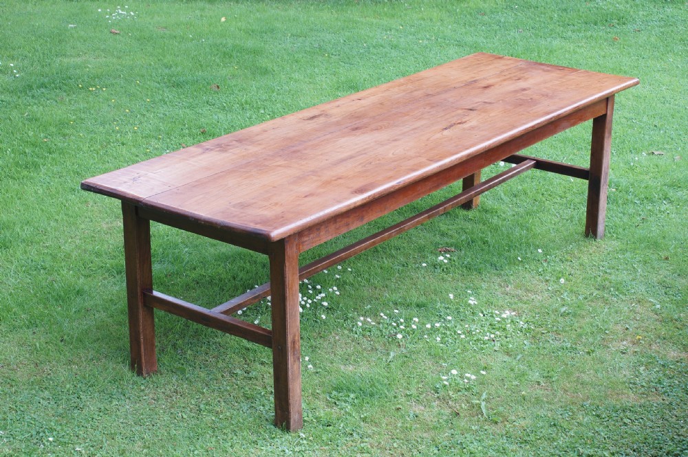 A rectangular 19th-century French cherry wood dining table featuring a plank top, straight legs, and lower H-stretchers.