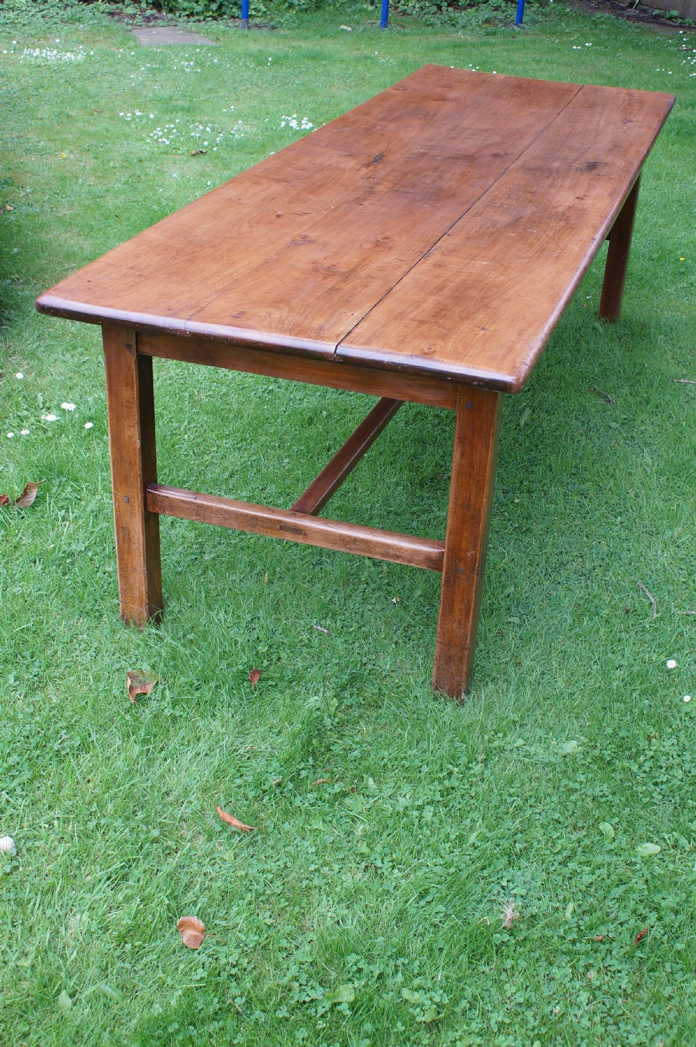 A rectangular 19th-century French cherry wood dining table featuring a plank top, straight legs, and lower H-stretchers. View X