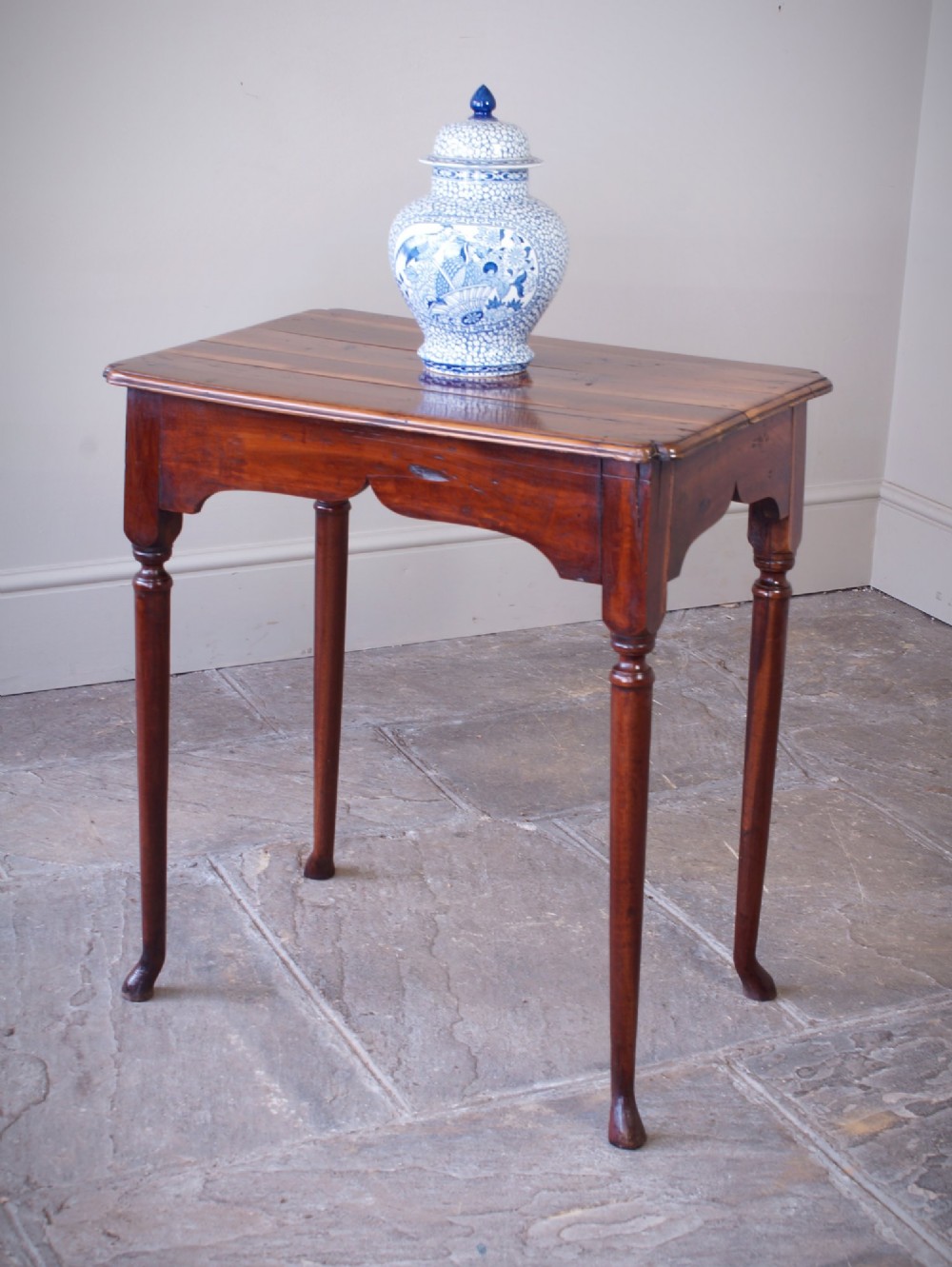 An early 18th-century fruitwood centre table featuring a rectangular plank top, a scalloped apron, and slender turned legs ending in pad feet. View IV