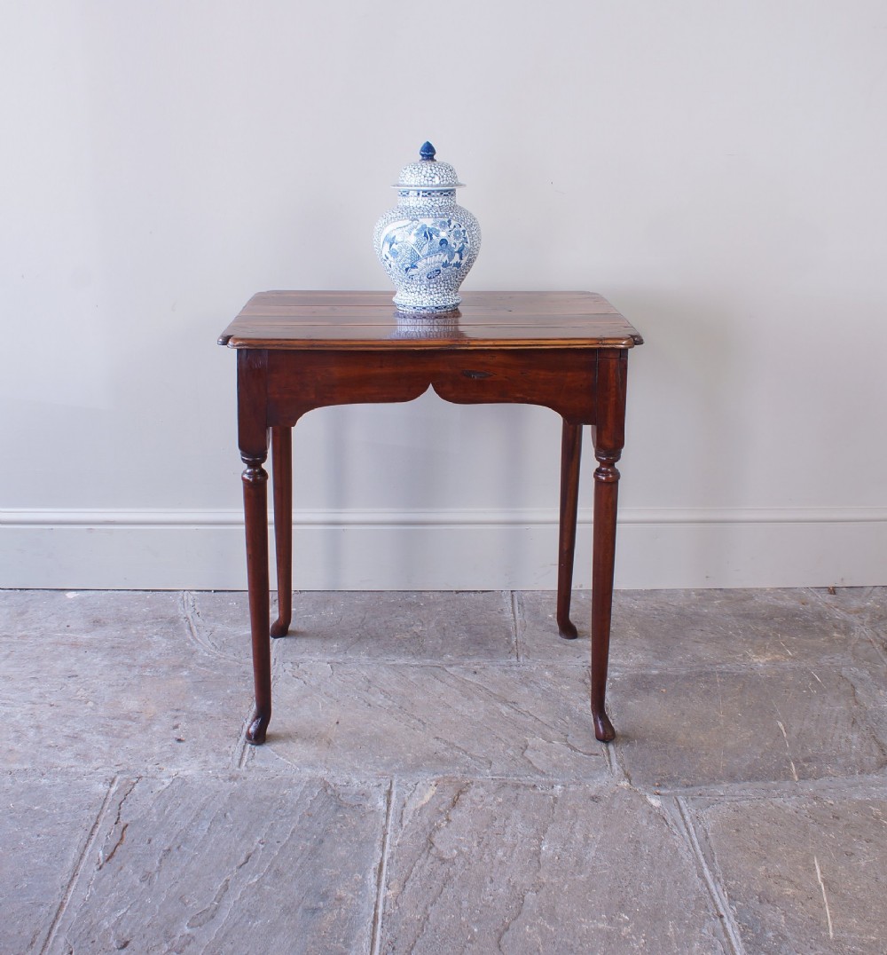 An early 18th-century fruitwood centre table featuring a rectangular plank top, a scalloped apron, and slender turned legs ending in pad feet. View V