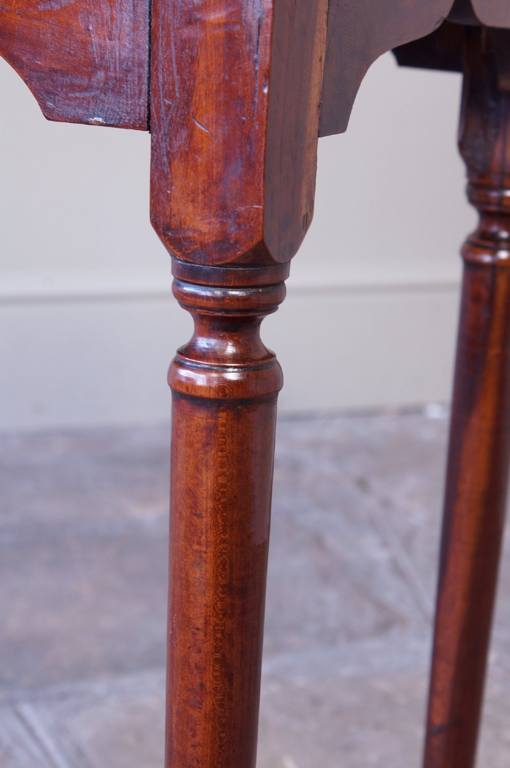 An early 18th-century fruitwood centre table featuring a rectangular plank top, a scalloped apron, and slender turned legs ending in pad feet. View VII