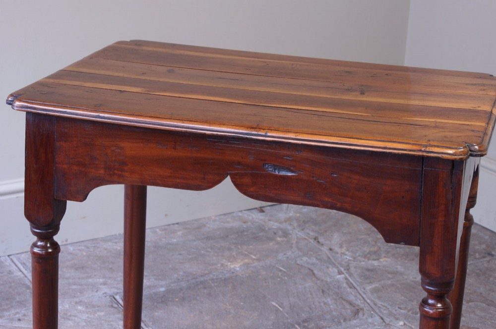 An early 18th-century fruitwood centre table featuring a rectangular plank top, a scalloped apron, and slender turned legs ending in pad feet. View XIV