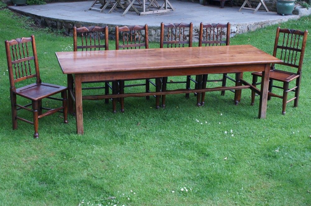 A set of six dark oak country dining chairs featuring carved shell crest rails, spindle backs, turned legs, and solid wood panel seats. View VII