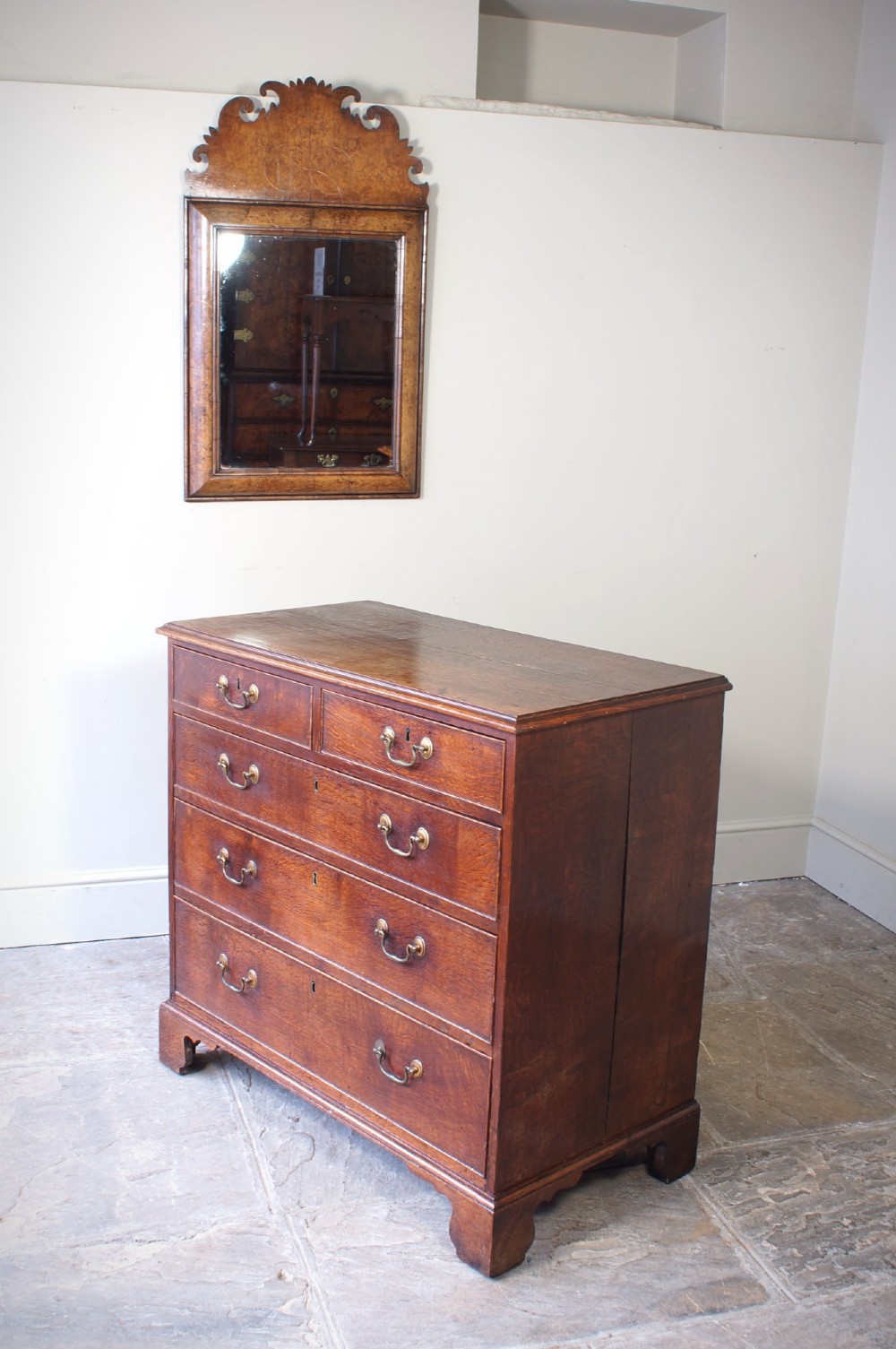 A Georgian oak chest of drawers featuring two short over three long graduated drawers with brass swan-neck handles and bracket feet. View III