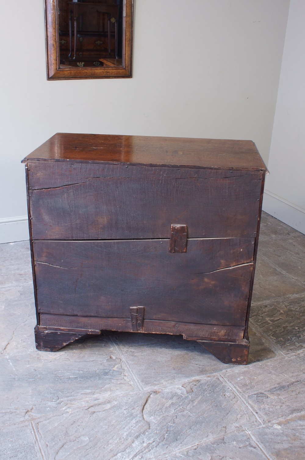 A Georgian oak chest of drawers featuring two short over three long graduated drawers with brass swan-neck handles and bracket feet. View V