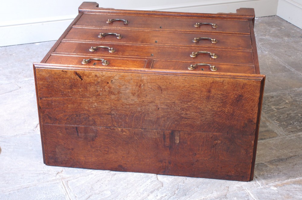 A Georgian oak chest of drawers featuring two short over three long graduated drawers with brass swan-neck handles and bracket feet. View VI