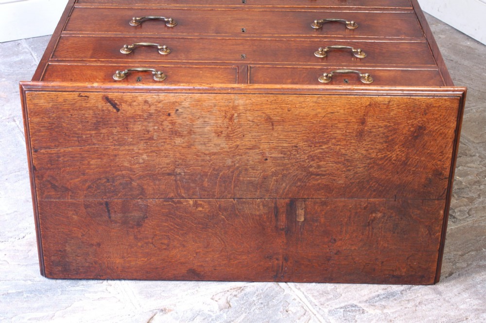 A Georgian oak chest of drawers featuring two short over three long graduated drawers with brass swan-neck handles and bracket feet. View IX
