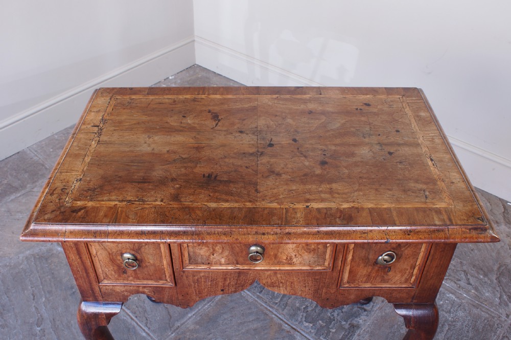 An early 18th-century walnut lowboy table with three drawers, brass ring pull handles, a scalloped apron, and cabriole legs ending in pad feet. View VII