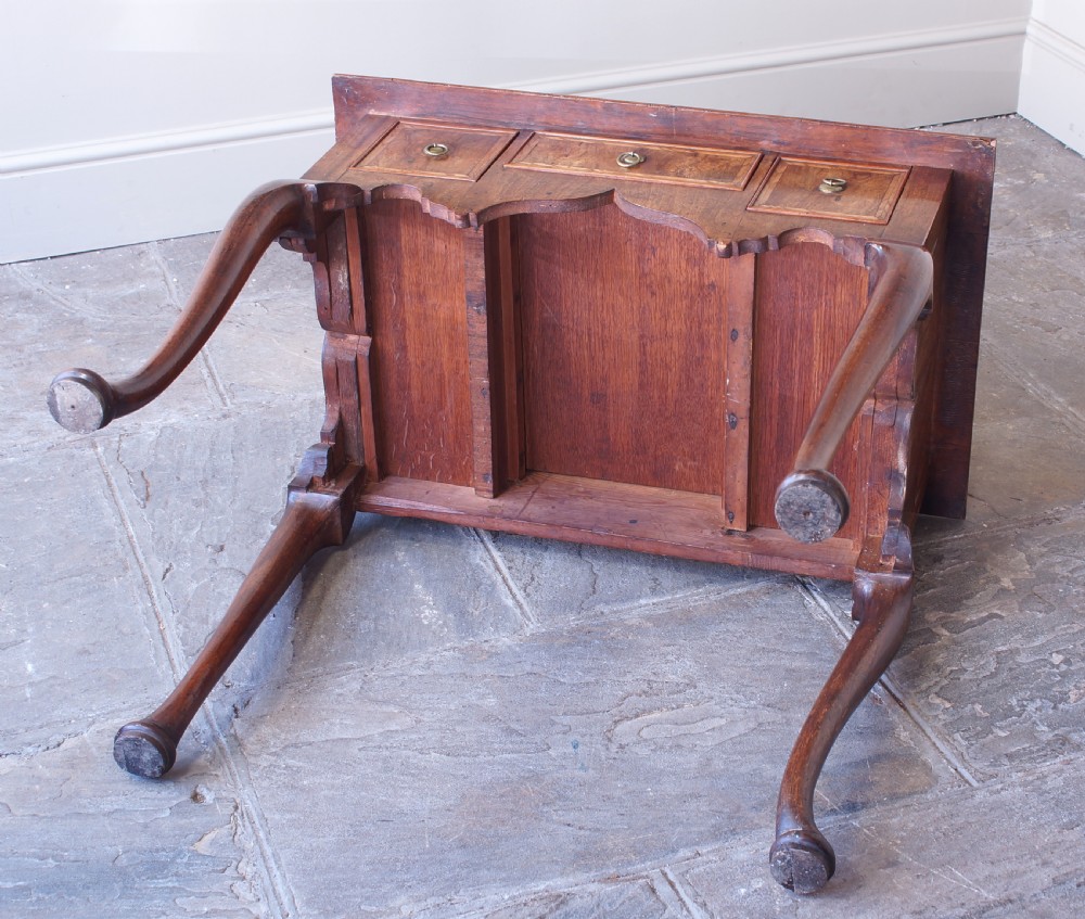 An early 18th-century walnut lowboy table with three drawers, brass ring pull handles, a scalloped apron, and cabriole legs ending in pad feet. View IX