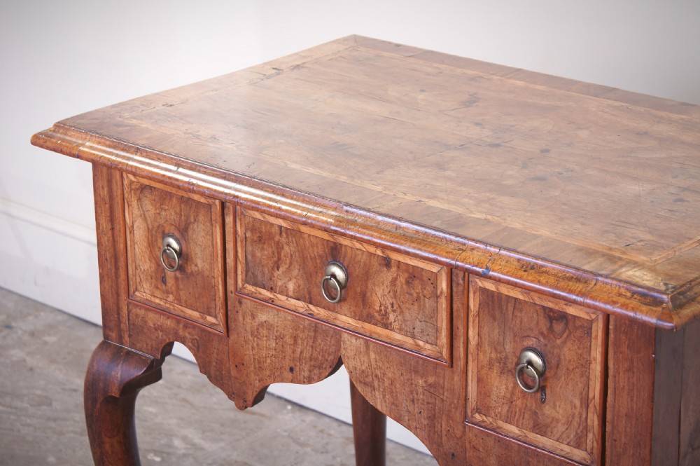 An early 18th-century walnut lowboy table with three drawers, brass ring pull handles, a scalloped apron, and cabriole legs ending in pad feet. View XI