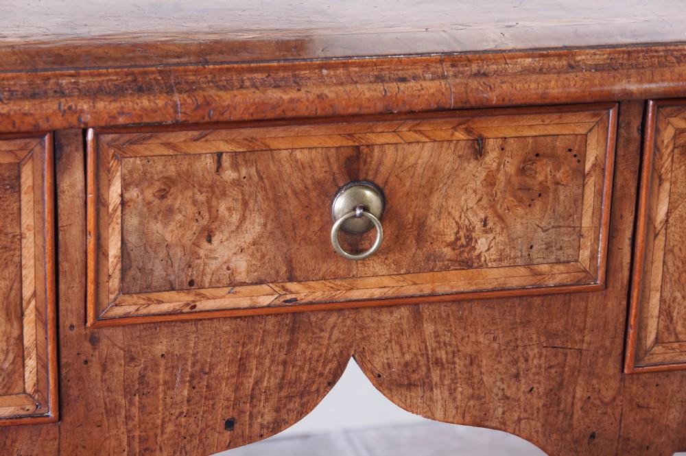 An early 18th-century walnut lowboy table with three drawers, brass ring pull handles, a scalloped apron, and cabriole legs ending in pad feet. View XII