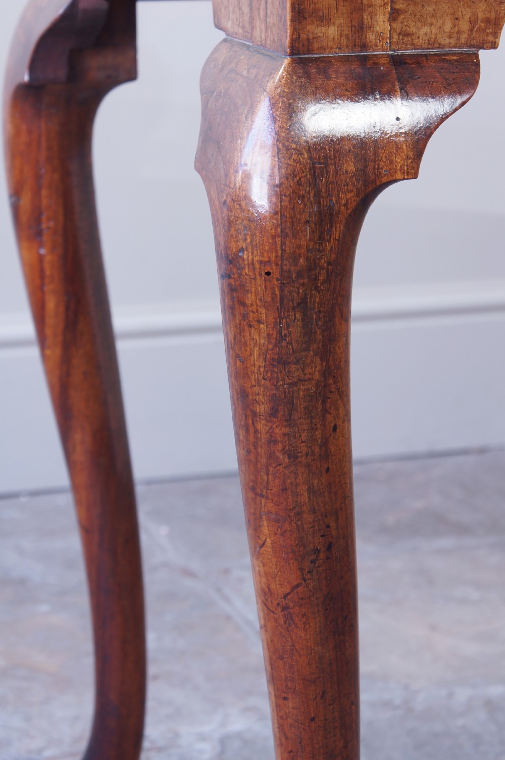 An early 18th-century walnut lowboy table with three drawers, brass ring pull handles, a scalloped apron, and cabriole legs ending in pad feet. View XVI