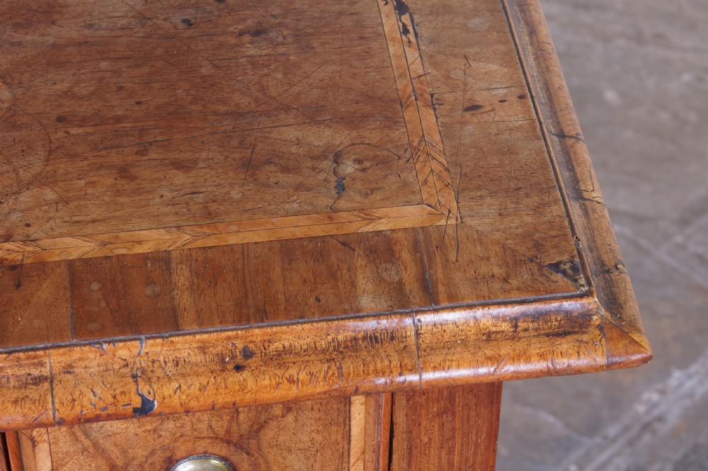 An early 18th-century walnut lowboy table with three drawers, brass ring pull handles, a scalloped apron, and cabriole legs ending in pad feet. View XVIII
