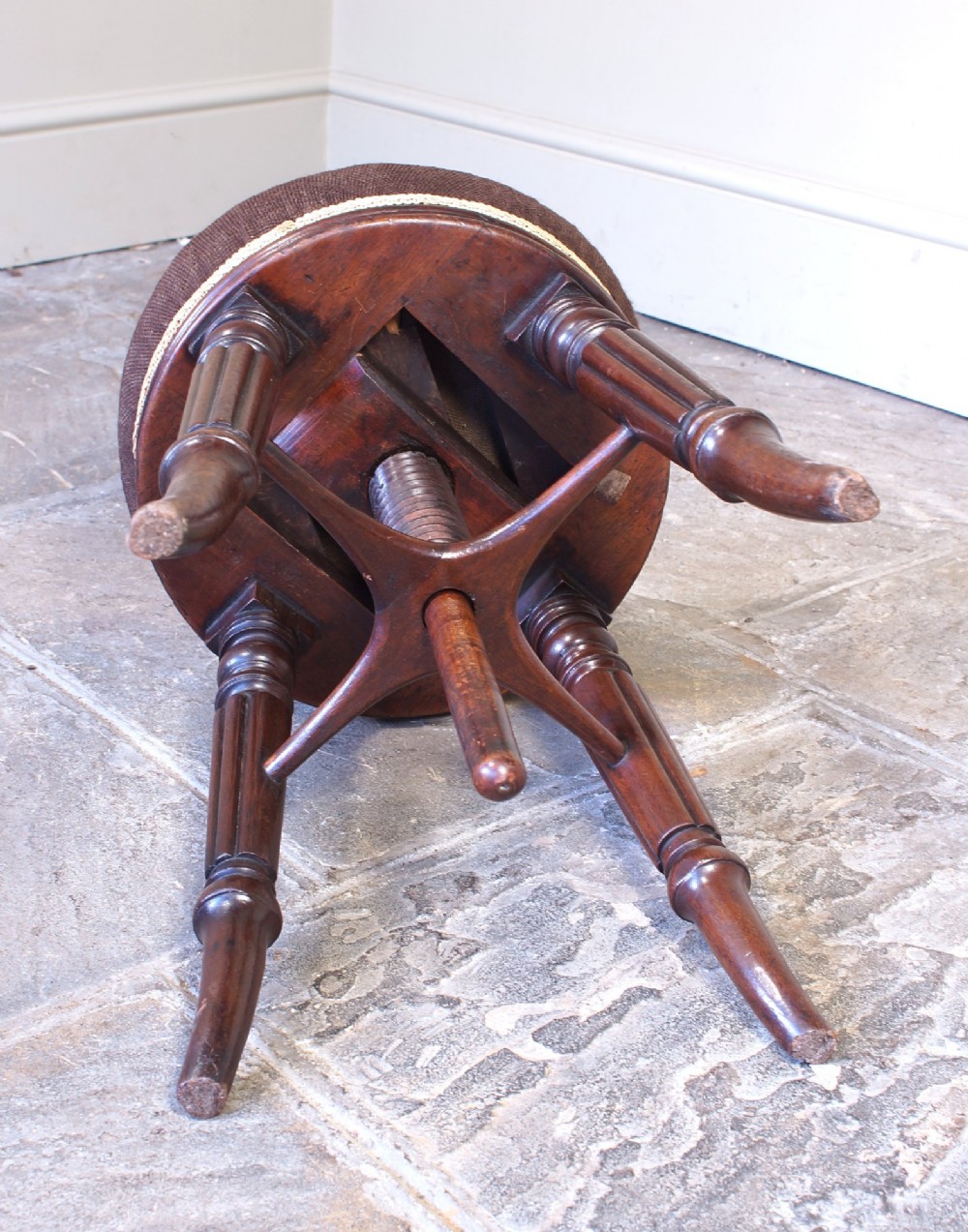 A Regency mahogany revolving piano stool featuring a circular floral needlepoint cushion, central wooden screw mechanism, and fluted turned legs. View VI