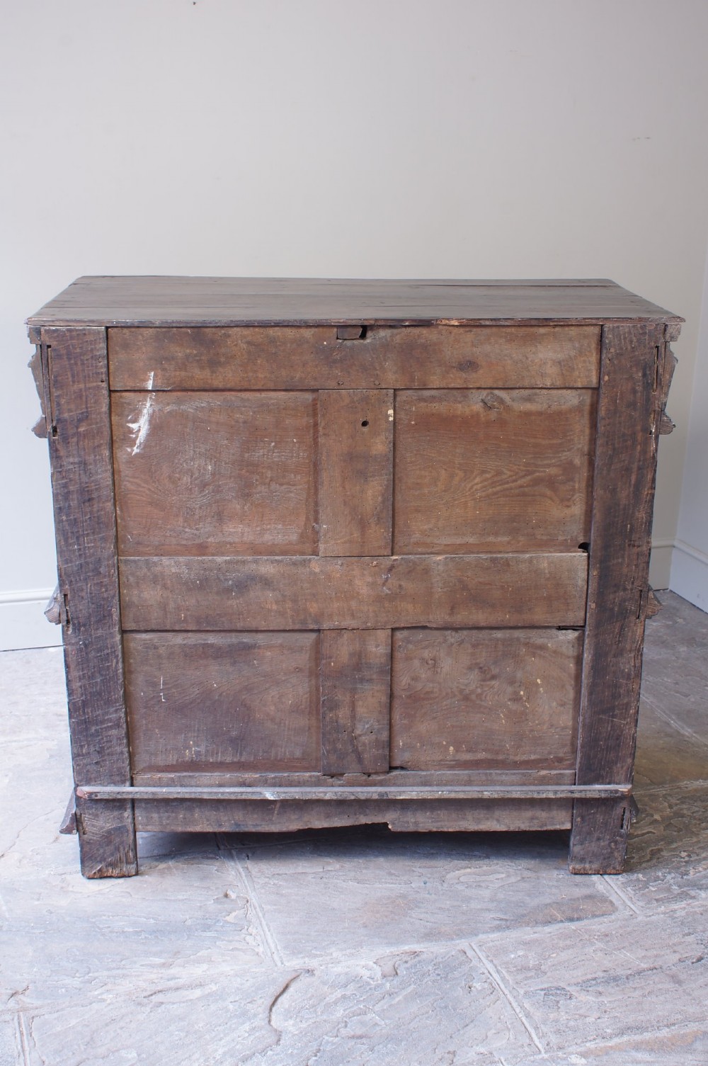 A 17th-century Charles II dark oak chest of drawers featuring geometric mitred panels, turned split spindles, brass drop handles, and bun feet. View IV