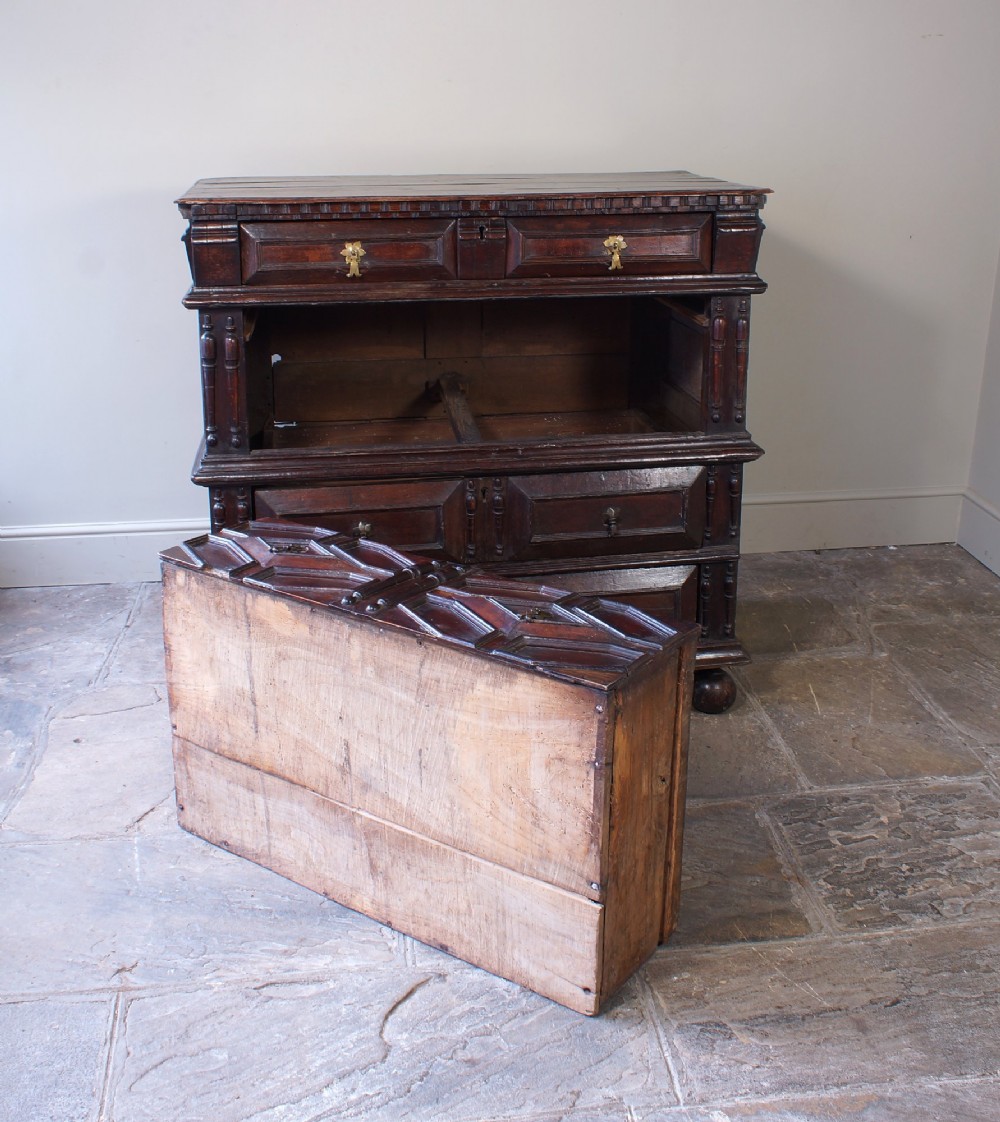 A 17th-century Charles II dark oak chest of drawers featuring geometric mitred panels, turned split spindles, brass drop handles, and bun feet. View VIII