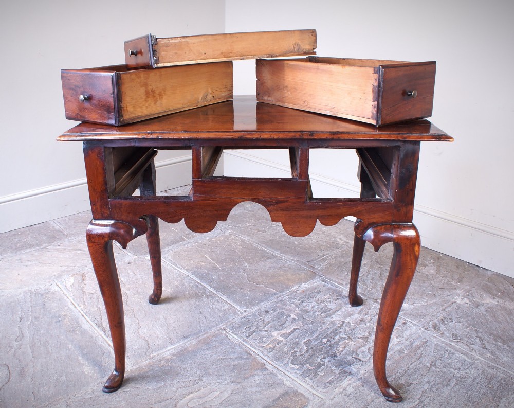 An 18th-century yew wood lowboy table featuring three drawers, a shaped scalloped apron, metal knob handles, and cabriole legs. View III