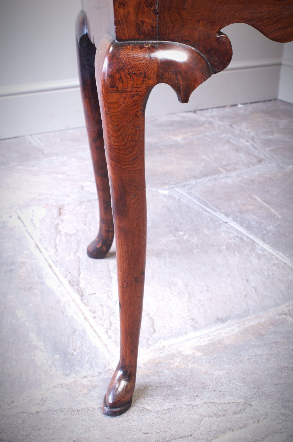 An 18th-century yew wood lowboy table featuring three drawers, a shaped scalloped apron, metal knob handles, and cabriole legs. View V