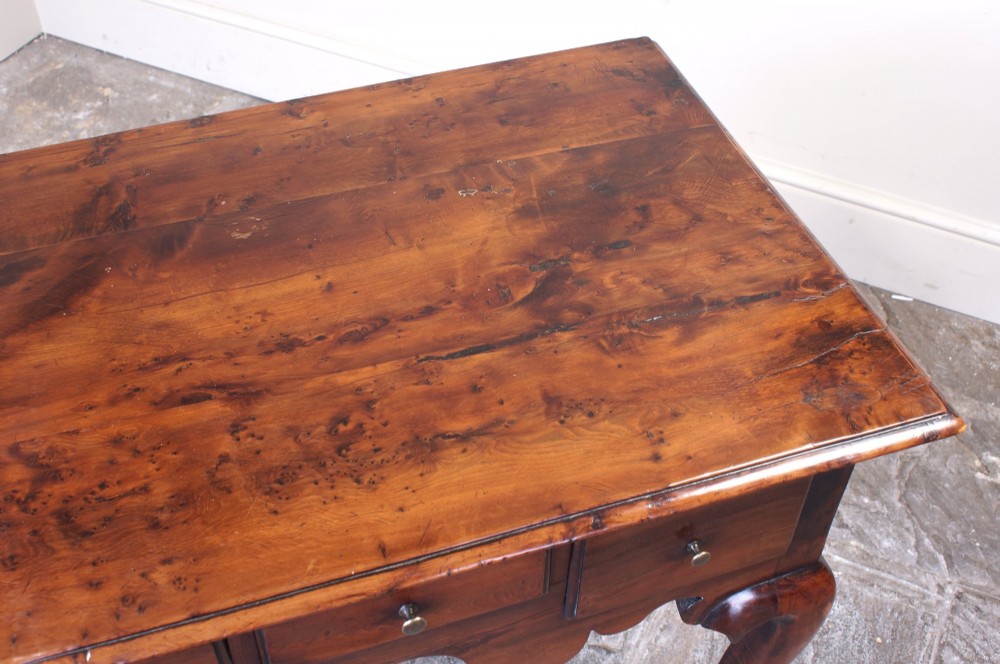 An 18th-century yew wood lowboy table featuring three drawers, a shaped scalloped apron, metal knob handles, and cabriole legs. View IX