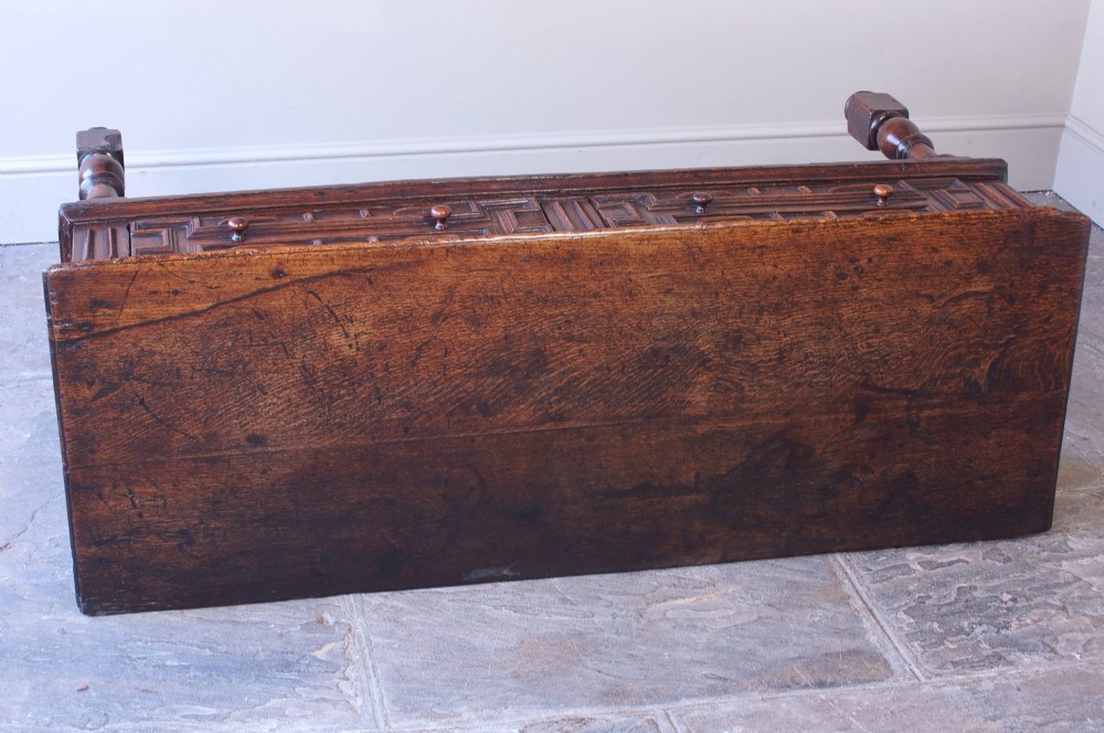 A 17th-century dark oak dresser base featuring geometric mitred mouldings across two drawers, turned front legs, and wooden drawer knobs. View VIII